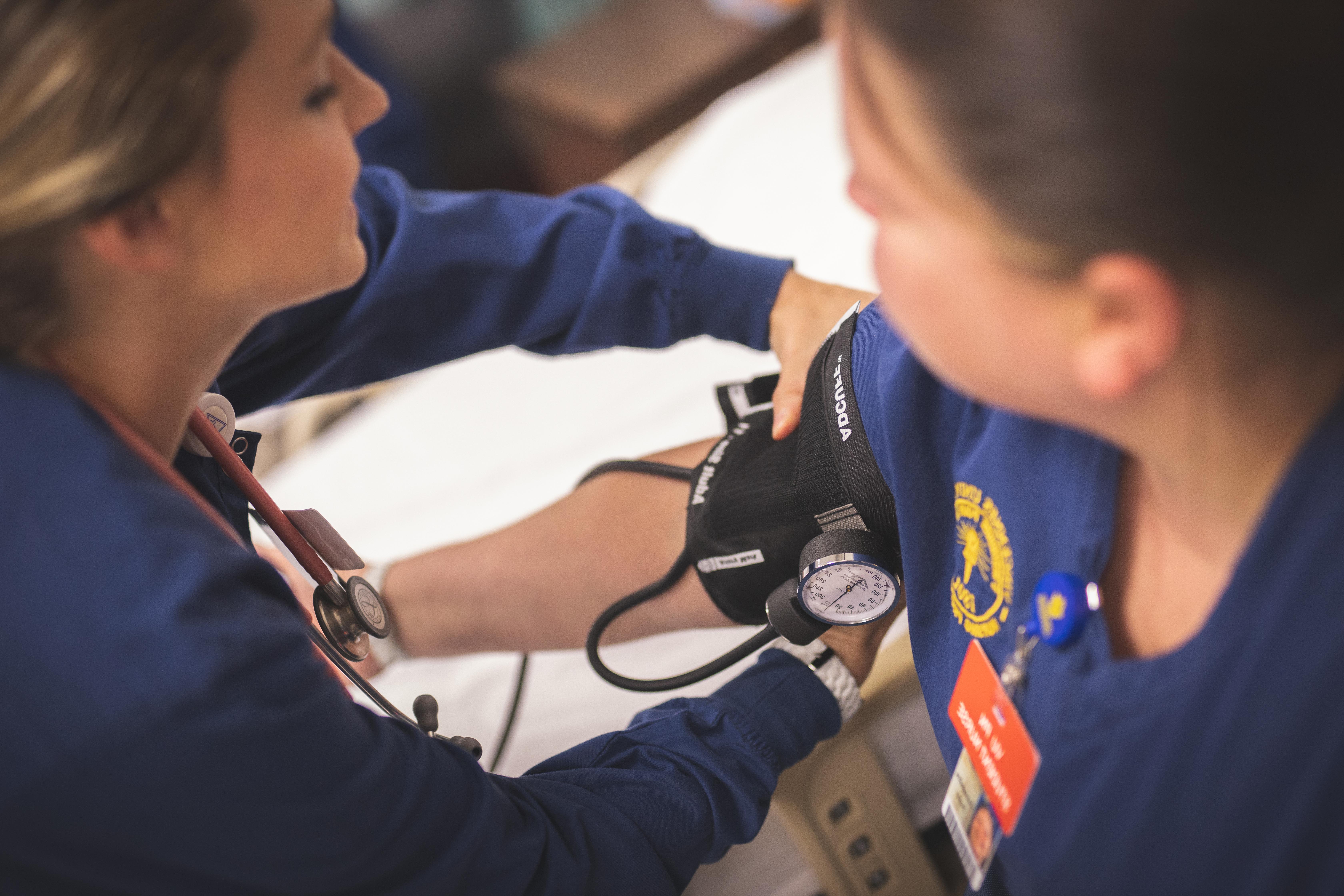 一个护理专业的学生在测量另一个学生的血压
