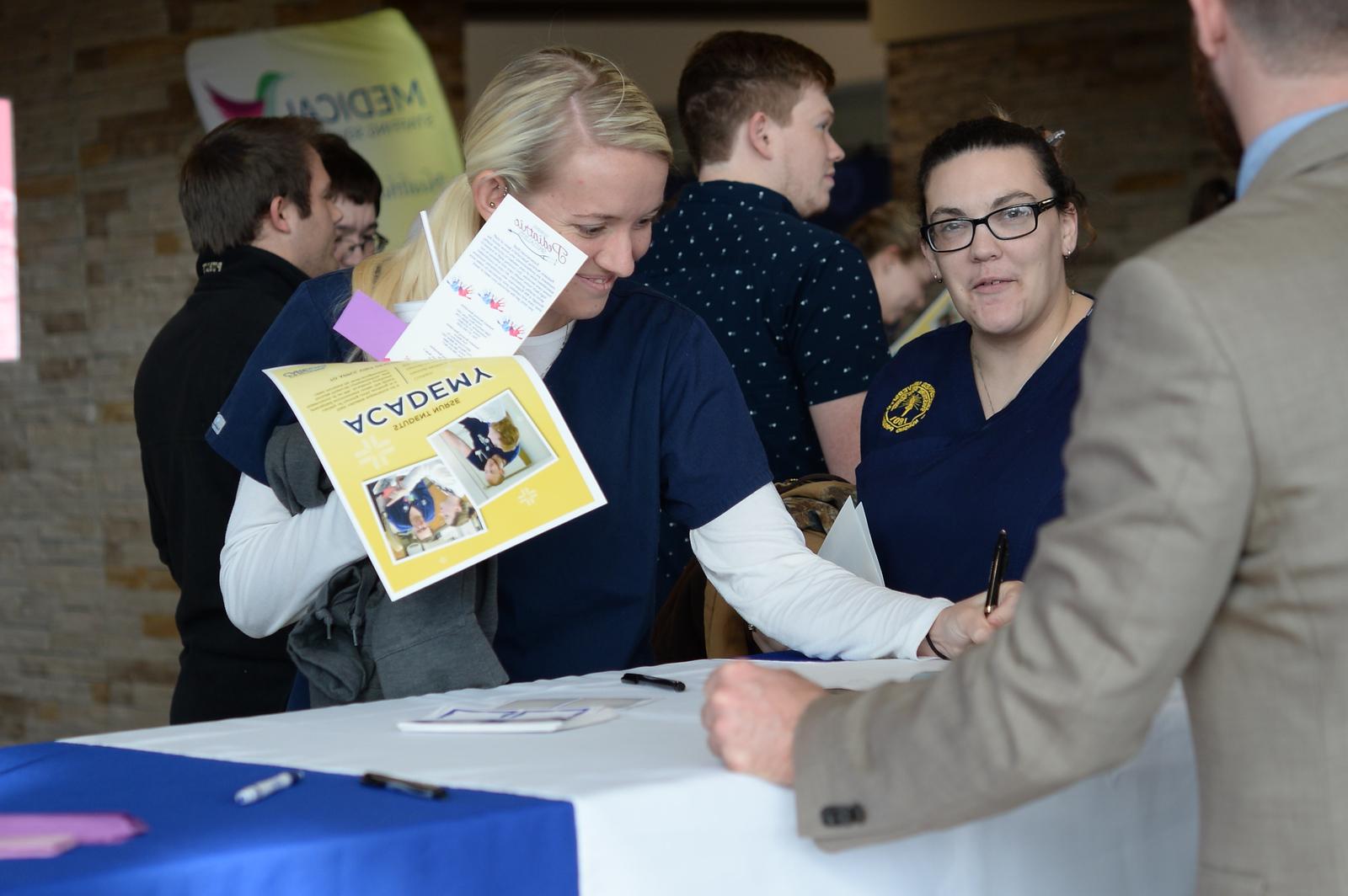 Nursing student signing a flyer at a job fair
