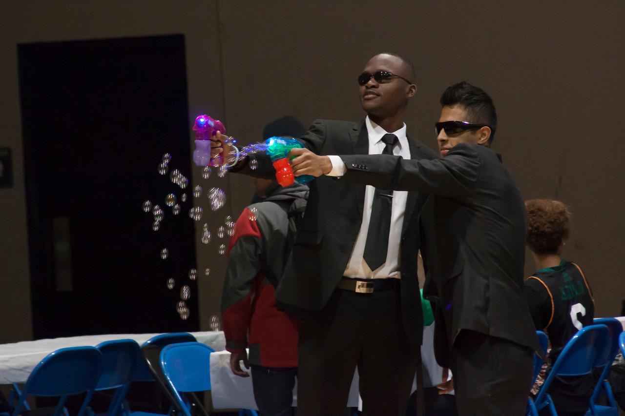 Two students in suits and sunglasses firing bubble guns