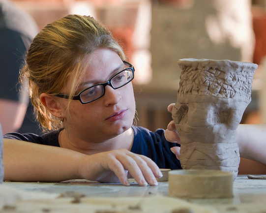 A female student making a sculpture out of clay