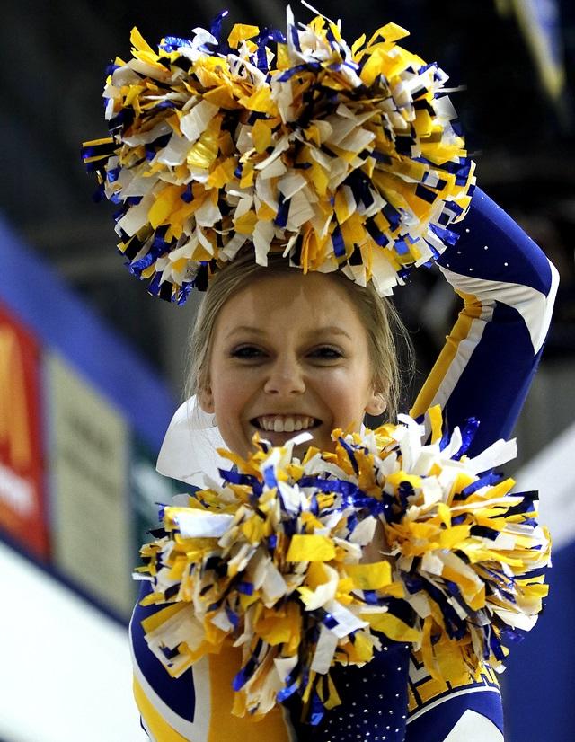A cheerleader holding a pair of pom poms